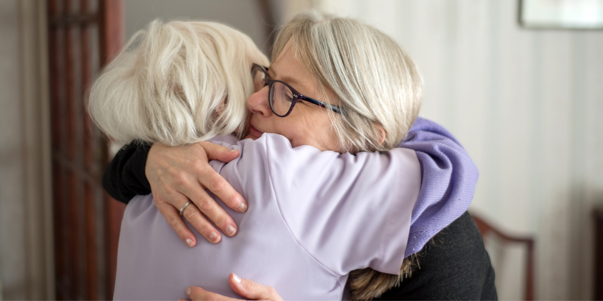 Deux personnes qui se soutiennent après la cérémonie funéraire.